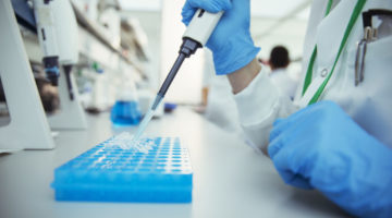Scientist pipetting samples into tray in laboratory